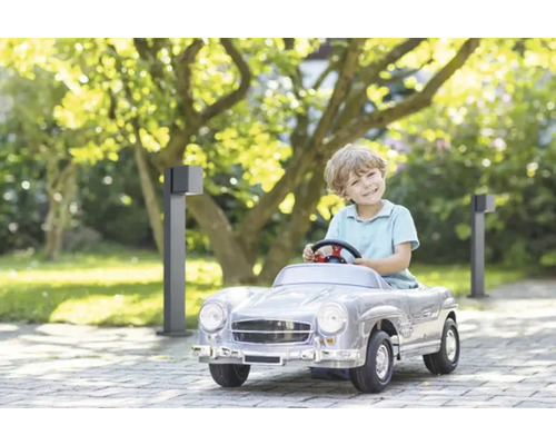 Băiat conduce o mașină de jucărie în grădină cu lumini de grădină