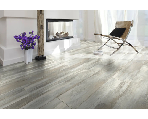 Cameră luminoasă cu șemineu, fotoliu și podea laminată cu aspect de lemn