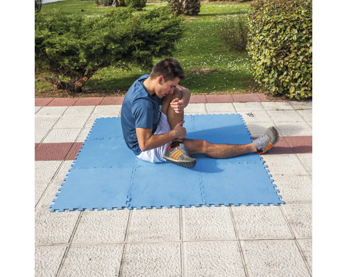 Bărbat întinzându-se pe o saltea de antrenament albastră afară