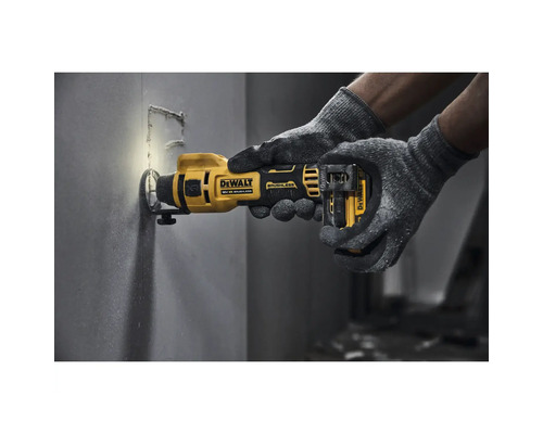 Unealtă multifuncțională cu acumulator Dewalt utilizată la tăierea unui perete de către o persoană cu mănuși