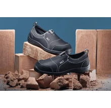 Doi pantofi de lucru negri cu cusături decorative albe pe cărămizi