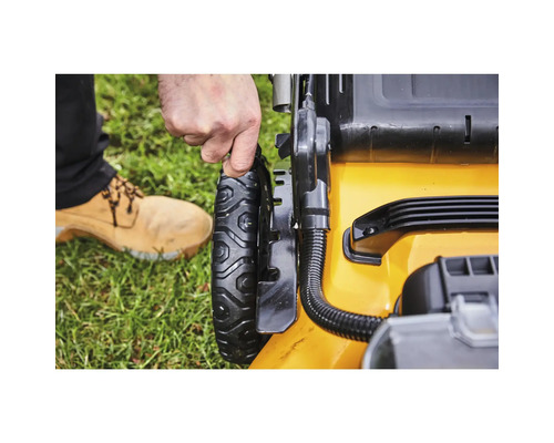 Prim-plan cu o mașină de tuns iarba galbenă cu o mână pe roată