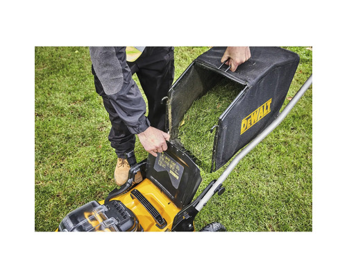 O persoană goleşte coşul colector de iarbă al unei maşini de tuns iarba pe un gazon. Logo Dewalt.