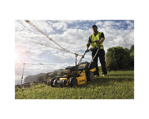 Un bărbat operează o mașină de tuns iarba cu acumulator DeWalt pe un gazon.