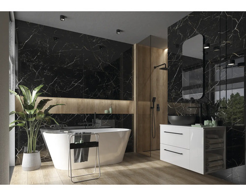 Baie luminoasă cu cadă de sine stătătoare, lavoar cu montare pe blat și plăci de perete cu aspect de marmură.