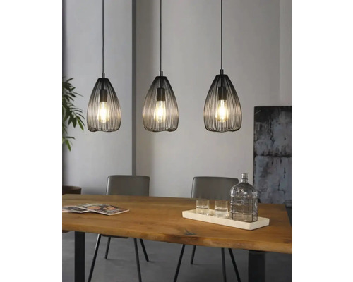 Trei lămpi suspendate metalice deasupra unei mese din lemn într-o sufragerie