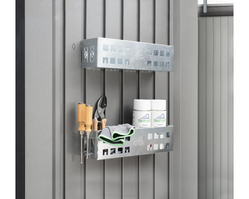 Două rafturi metalice cu scule, cârpe de curățat și spray-uri pe un perete