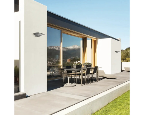 Exteriorul unei case cu masă, scaune și lumini exterioare