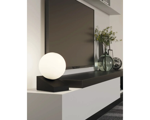 Scenă decorativă de living cu un televizor modern, o lampă de masă minimalistă în formă de sferă și vaze decorative pe o comodă TV elegantă.