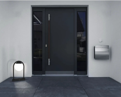 Zonă de intrare cu ușă de intrare, ferestre laterale, cutie poștală și lampă de exterior.