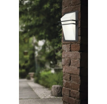 Lumină de perete exterioară pe un perete de cărămidă cu o grădină în fundal