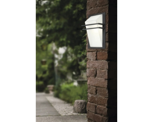 Lumină de perete exterioară pe un perete de cărămidă cu o grădină în fundal
