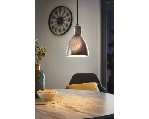 Lampa suspendată metalică deasupra unei mese de sufragerie într-o sufragerie.