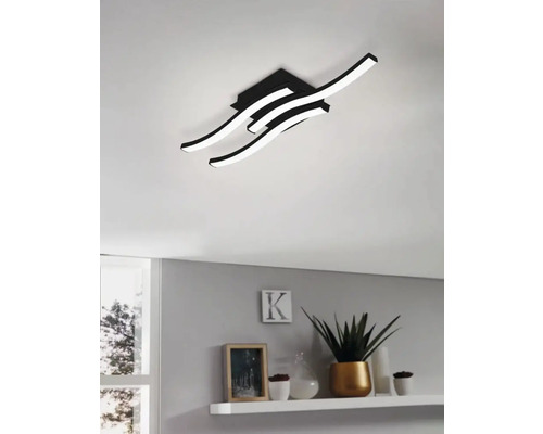 Plafonieră modernă cu elemente de lumină curbate într-un spațiu de locuit.
