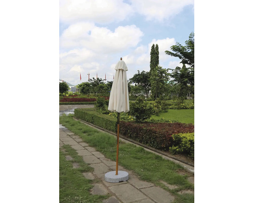 Umbrelă de soare închisă cu suport într-o grădină.