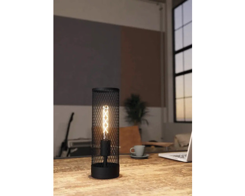 Scenă de birou cu o lampă de masă neagră din plasă metalică cu bec