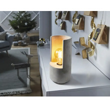 Lampă de masă decorativă din beton lângă un calendar de advent într-un living.