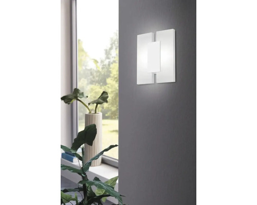 Lumină de perete albă cu design modern lângă o plantă de interior
