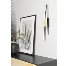 Lampa modernă de perete din metal lângă imaginea înrămată