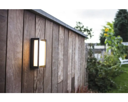 Lumină de perete exterioară pe un perete de lemn într-o grădină