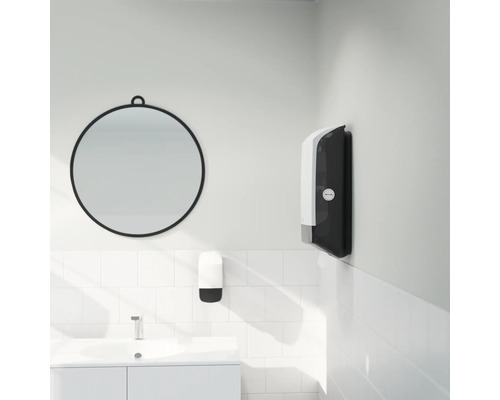 Baie modernă cu oglindă rotundă, dozator de săpun și dispenser de prosoape de hârtie pe perete