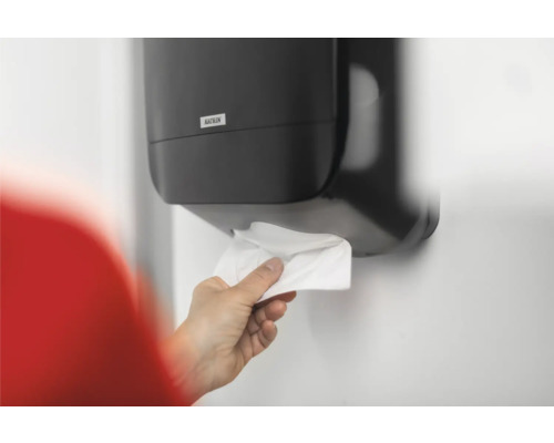 O persoană ia un prosop de hârtie dintr-un dispenser Katrin.