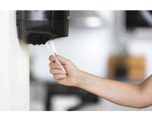 O mână ia un prosop de hârtie dintr-un dispenser.