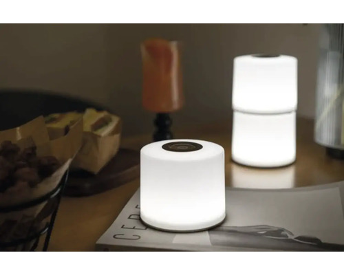 Scenă cu două lămpi de masă cilindrice luminoase pe o masă