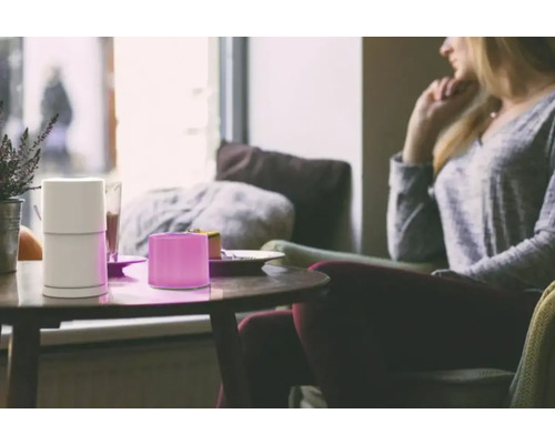 Scenă cu umidificator de aer pe o masă lângă o persoană așezată.