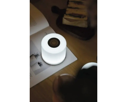 Lampă de masă cu difuzor pe o masă lângă o carte și mâncare