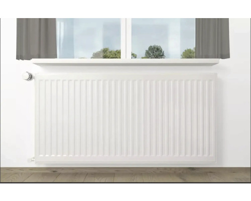 Calorifer alb sub o fereastră într-o cameră.