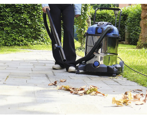 O persoană folosește un aspirator umed uscat afară pentru a îndepărta frunzele.