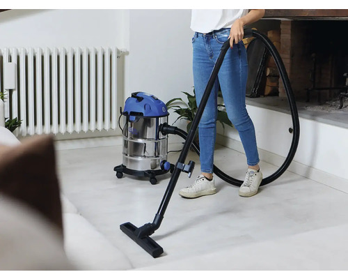 O persoană folosește un aspirator umed uscat pentru a curăța podeaua dintr-o cameră de zi.