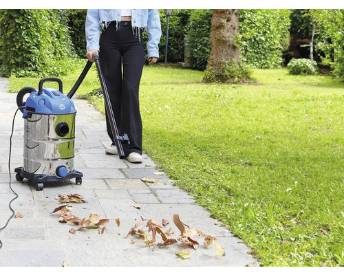 O persoană folosește un aspirator universal în grădină pentru a îndepărta frunzele.