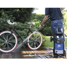 Persoană care curăță o bicicletă cu un curățător cu presiune afară