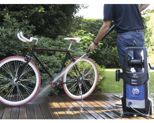 Persoană care curăță o bicicletă cu un curățător cu presiune afară