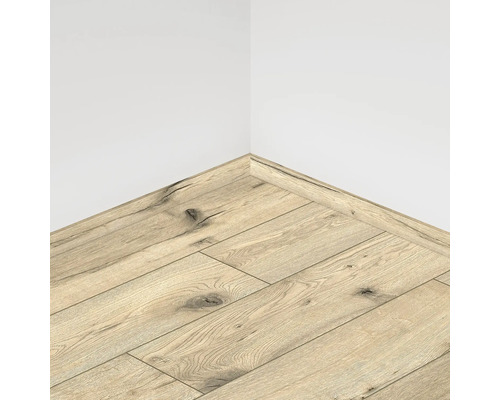 Colțul unei camere cu podea laminată și plintă asortată