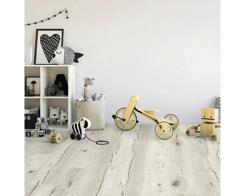 Cameră luminoasă pentru copii cu jucării, inclusiv un raft și un vehicul din lemn pe o podea din lemn.