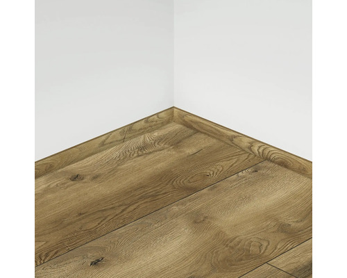 Vedere din colț a pardoselii laminate cu plintă asortată pe un perete alb