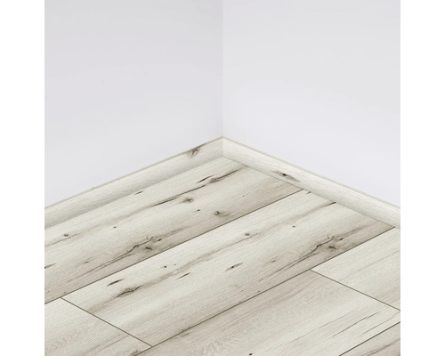 Pardoseală laminată deschisă la culoare cu plintă pe un perete alb