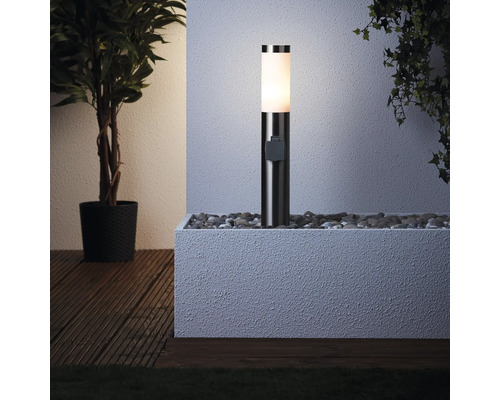 Lumină soclu iluminată într-o jardinieră plină cu pietre lângă o plantă