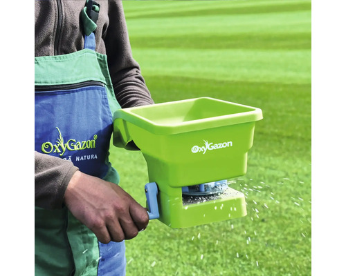 Persoană care utilizează un distribuitor manual pentru îngrijirea gazonului de la OxyGazon.
