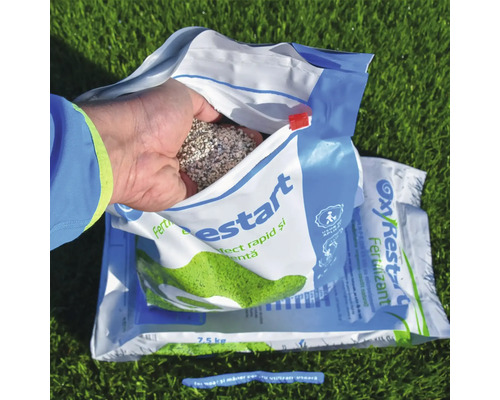 Pachet deschis de îngrășământ pentru gazon cu mână care ține îngrășământ