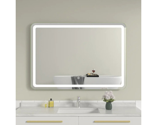 Oglindă de baie iluminată deasupra unei chiuvete cu robinet și flori